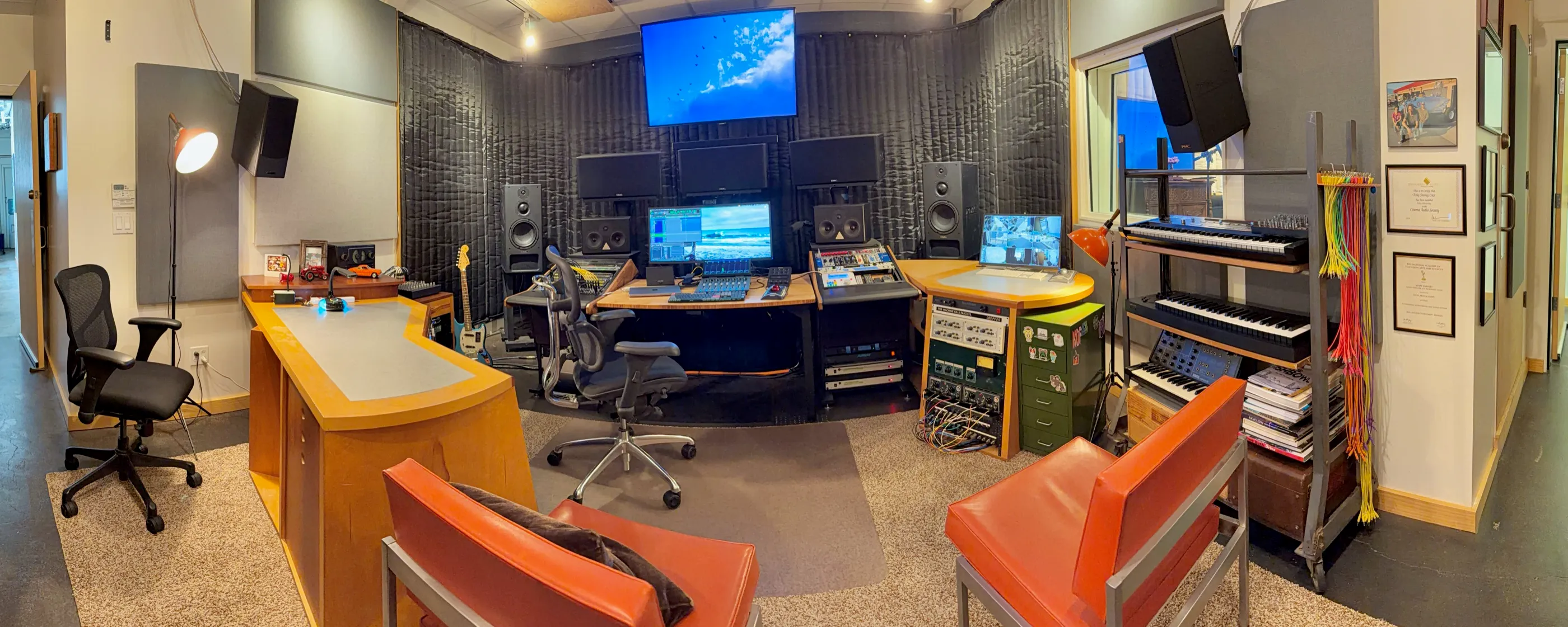 The BENDYsound mix stage in Inglewood: wood desks, orange client chairs, PMC monitors, and the Atmos picture wall.